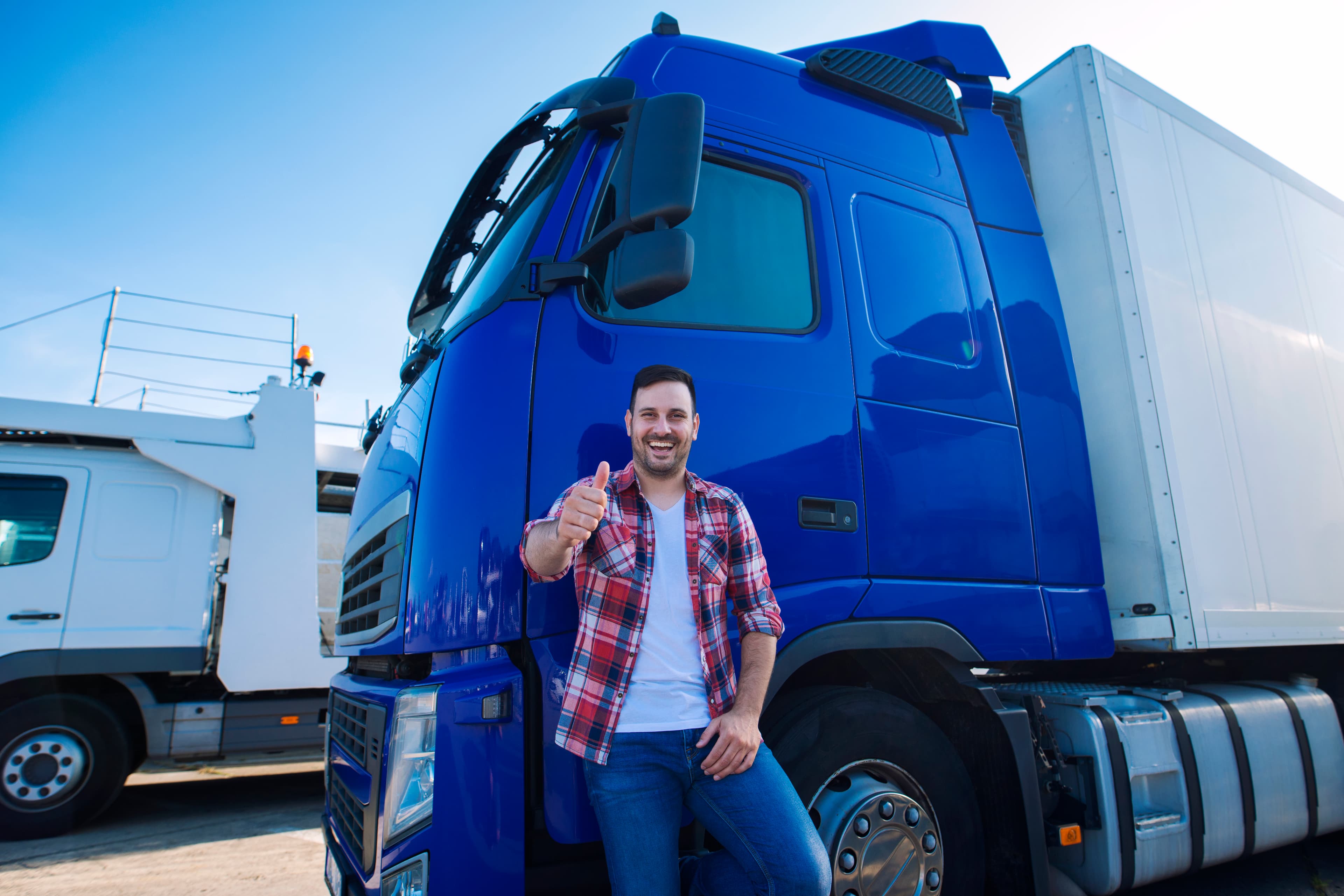 Professional truck driver giving a thumbs up in front of a long-haul transportation vehicle