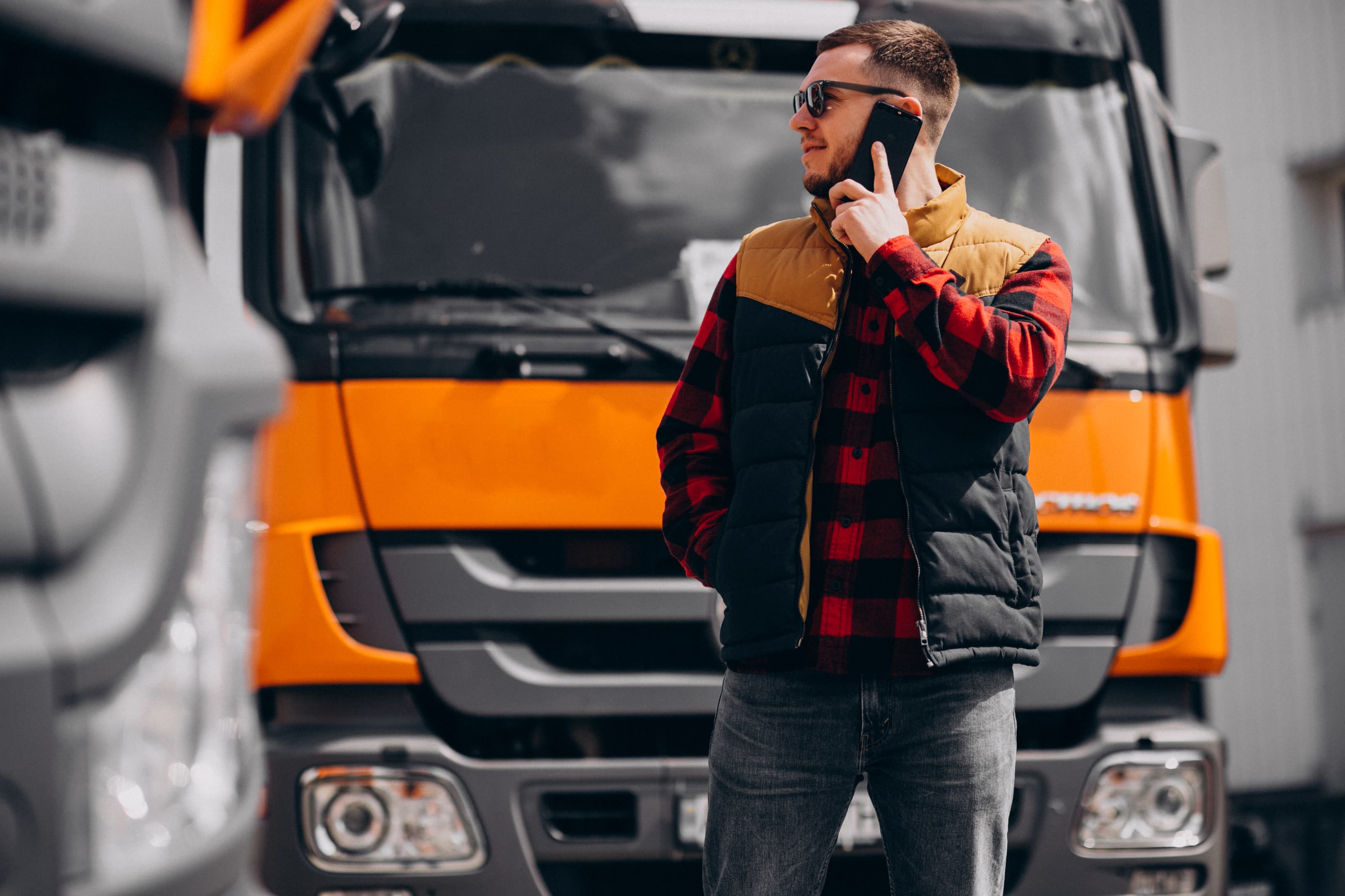 Truck driver on a call beside a commercial haulage vehicle